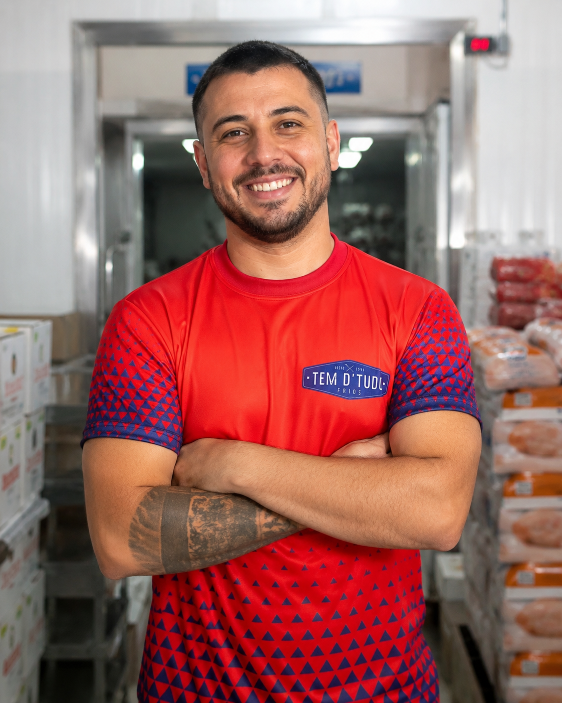 Homem sorrindo vestindo camisa promocional vermelha com estampa geométrica da Tem D'Tudo